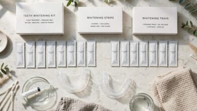 A flat-lay of at-home teeth whitening products, including strips and trays, on a bathroom counter.