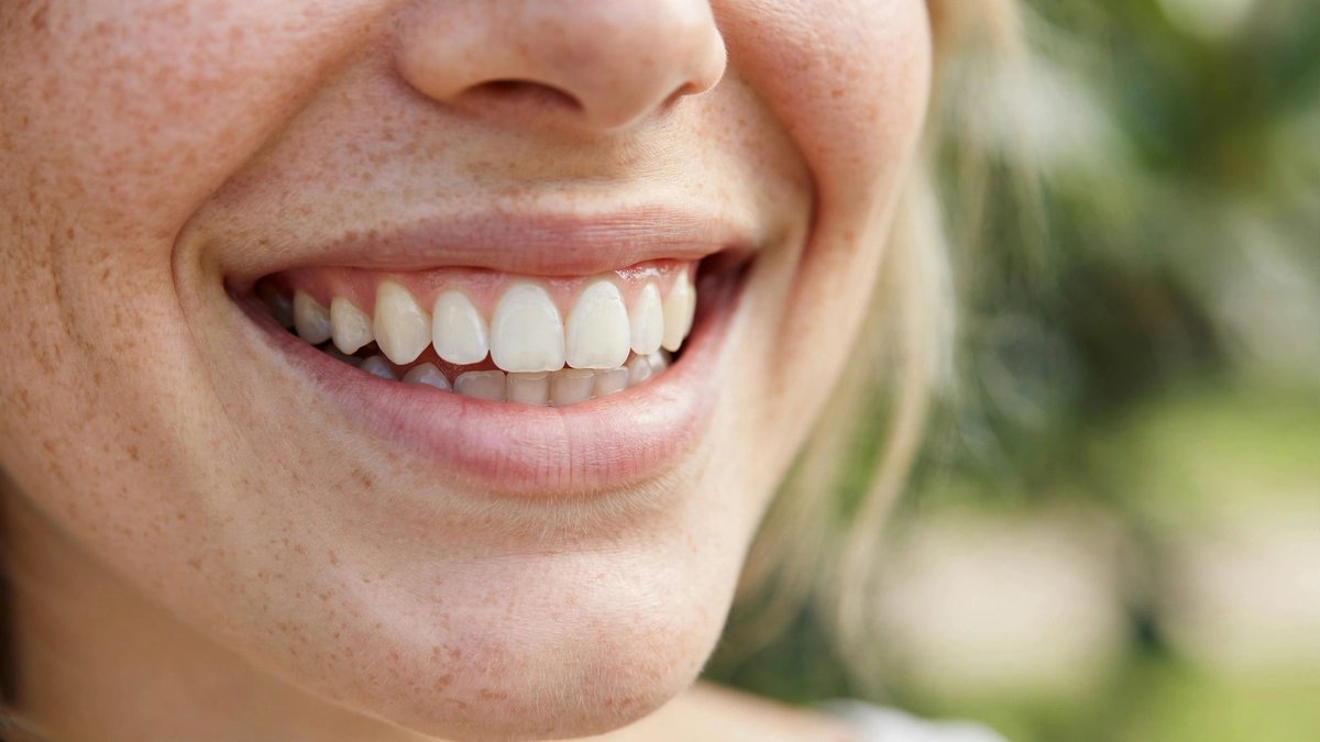A close-up of a natural, bright and healthy smile in soft daylight.